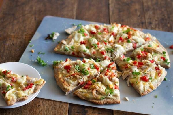 Chicken Alfredo pizza slices on a pan.